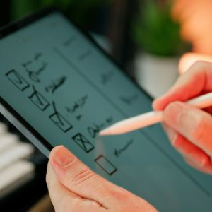 A pair of hands are holding an iPad marking off items from a checklist.