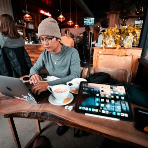 a man doing work at a coffee shop with a laptop and ipad