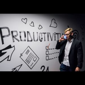 a business man with a dry erase board behind him that says productivity and graphics drawn onto it