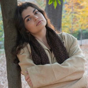 A young woman leaning on a tree.