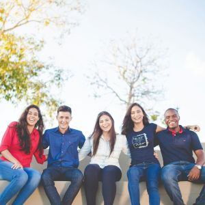 A group of young leaders sitting next to each other outside for a picture.