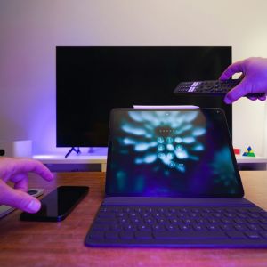 A man with a computer, distracted by a television.