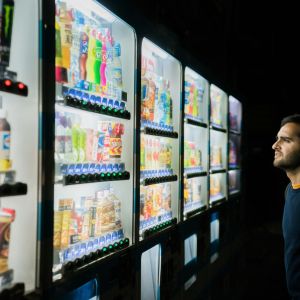 A man standing at a high tech vending machine.