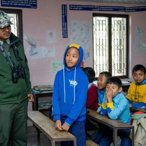 A confused child standing at his seat, in front of the class, trying to explain something.