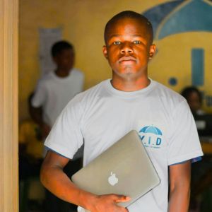 A young boy is standing with a laptop in his hand.