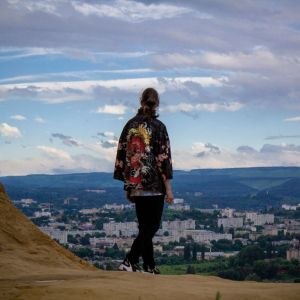 A man is an Asian inspired outfit, looking at a view.