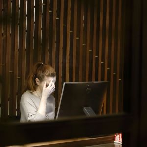 A frustrated woman, sitting at a computer.
