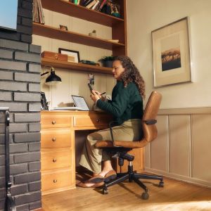 A woman is on her phone while at her work desk.