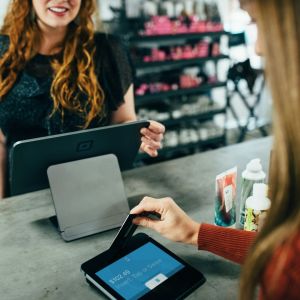 Two women with computers but one is processing a payment.